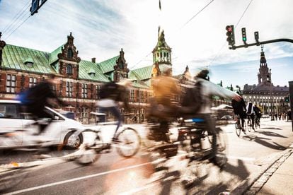 Ciclistas em Copenhague, com o edifício da Bolsa ao fundo