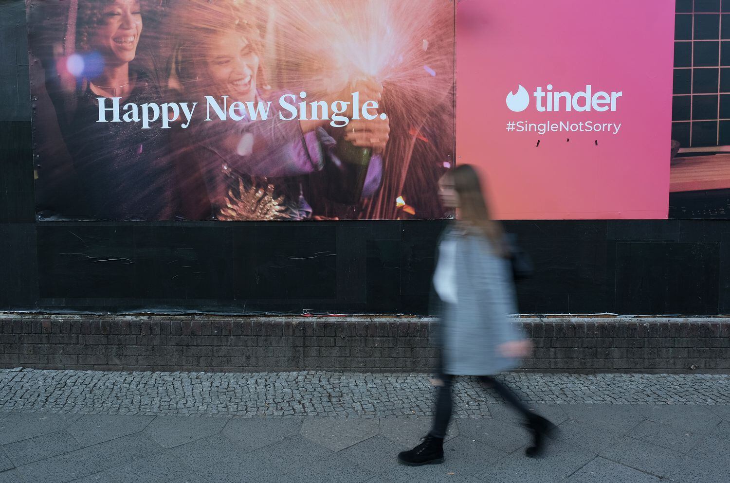 Mulher passa diante de um anúncio do aplicativo de encontros Tinder.