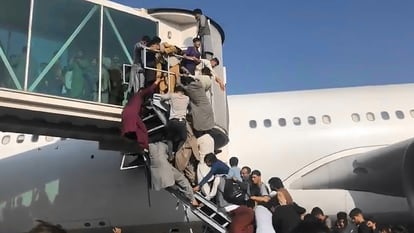 Afegãos tentam acessar um avião no aeroporto de Cabul na segunda-feira.