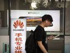 Homem caminha ao lado de uma loja com anúncios da Huawei e da Apple, em Pequim, na sexta-feira.