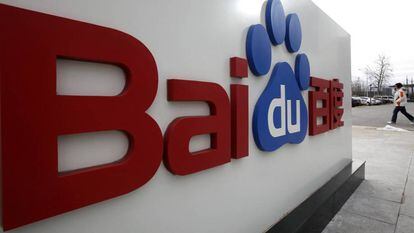 Uma mulher caminha junto ao logótipo de Baidu em sua sede de Beijing.