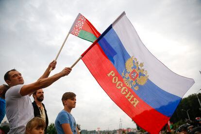 Manifestante leva uma bandeira russa e outra de Belarus em apoio a Lukashenko, nesta quinta.