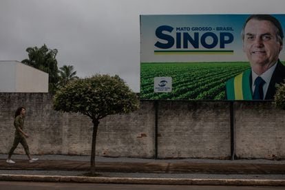 Pessoa caminha perto de um cartaz de apoio ao presidente em Sinop, berço da indústria da soja e bastião eleitoral de Bolsonaro.