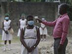 Un maestro toma la temperatura de los estudiantes de la Escuela Modelo del Estado de Lagos, con mascarilla para protegerse contra el coronavirus. Las escuelas públicas y privadas reanudaron las clases el lunes después de meses de cierre para frenar la propagación de la covid-19. 