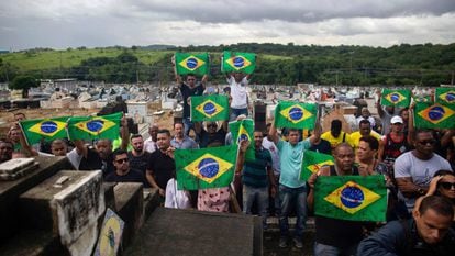 Manifestantes levam bandeiras do Brasil sujas de tinta vermelha em protesto no cemitério Ricardo de Albuquerque. no Rio, no último dia 10, contra a ação do Exército que causou duas mortes.