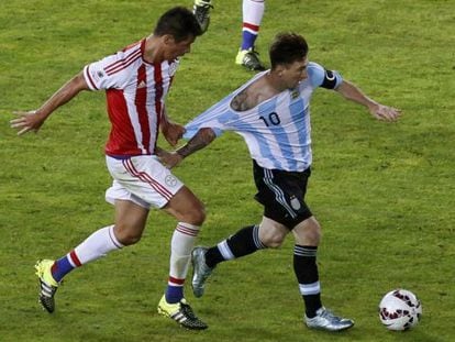 O meia paraguaio Victor Cáceres tentar frear Messi puxando sua camiseta durante o jogo de sábado.