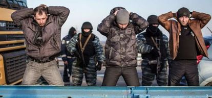 Forças pró-russas averiguam um grupo de homens na entrada da Crimeia, na segunda-feira.