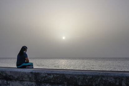 Uma mulher contempla a tempestade de areia do Saara na orla marítima de Havana, Cuba.