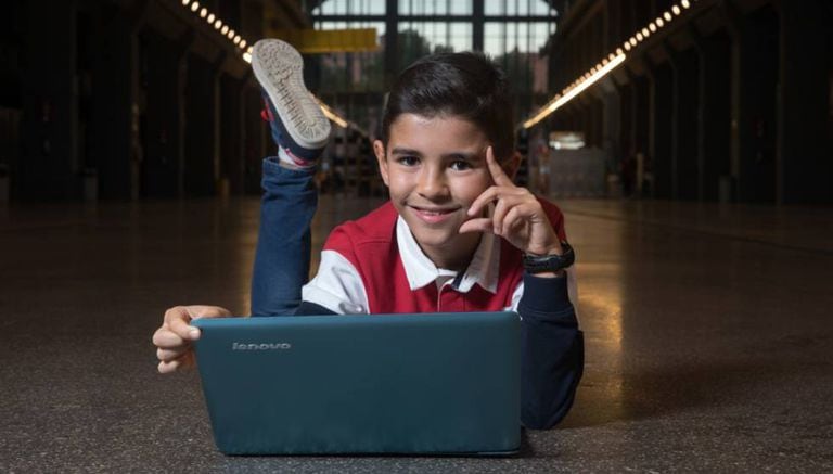 Antonio García Vicente, de 11 anos, posa com o computador no qual programa.