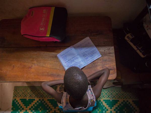 Leticia Amongin, de ocho años, hace los deberes con la poca luz que entra por la ventana de su casa, en Uganda. 