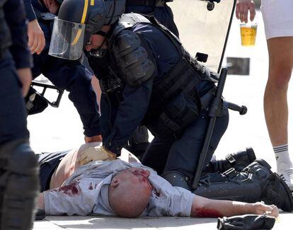 Um policial atende um torcedor britânico ferido após o jogo Inglaterra-Rússia