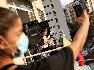 FILE PHOTO: Musician Zandu Montoya sings at the balcony of his house while a friend is recording with a cellphone during the national quarantine in response to the spread of coronavirus disease (COVID-19) in Caracas, Venezuela March 28, 2020. Picture taken March 28, 2020. REUTERS/Manaure Quintero/File Photo