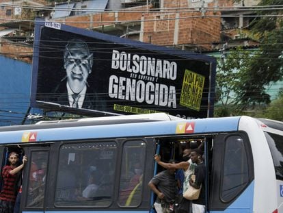 Passageiros circulam em ônibus lotado nesta terça-feira, no Rio de Janeiro, ao lado de outdoor crítico a Jair Bolsonaro.