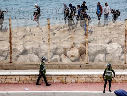Agentes de segurança marroquinos montam guarda enquanto um grupo de emigrantes caminha pela costa na cidade nortista de Fnideq, em uma tentativa de cruzar a fronteira nesta terça-feira.