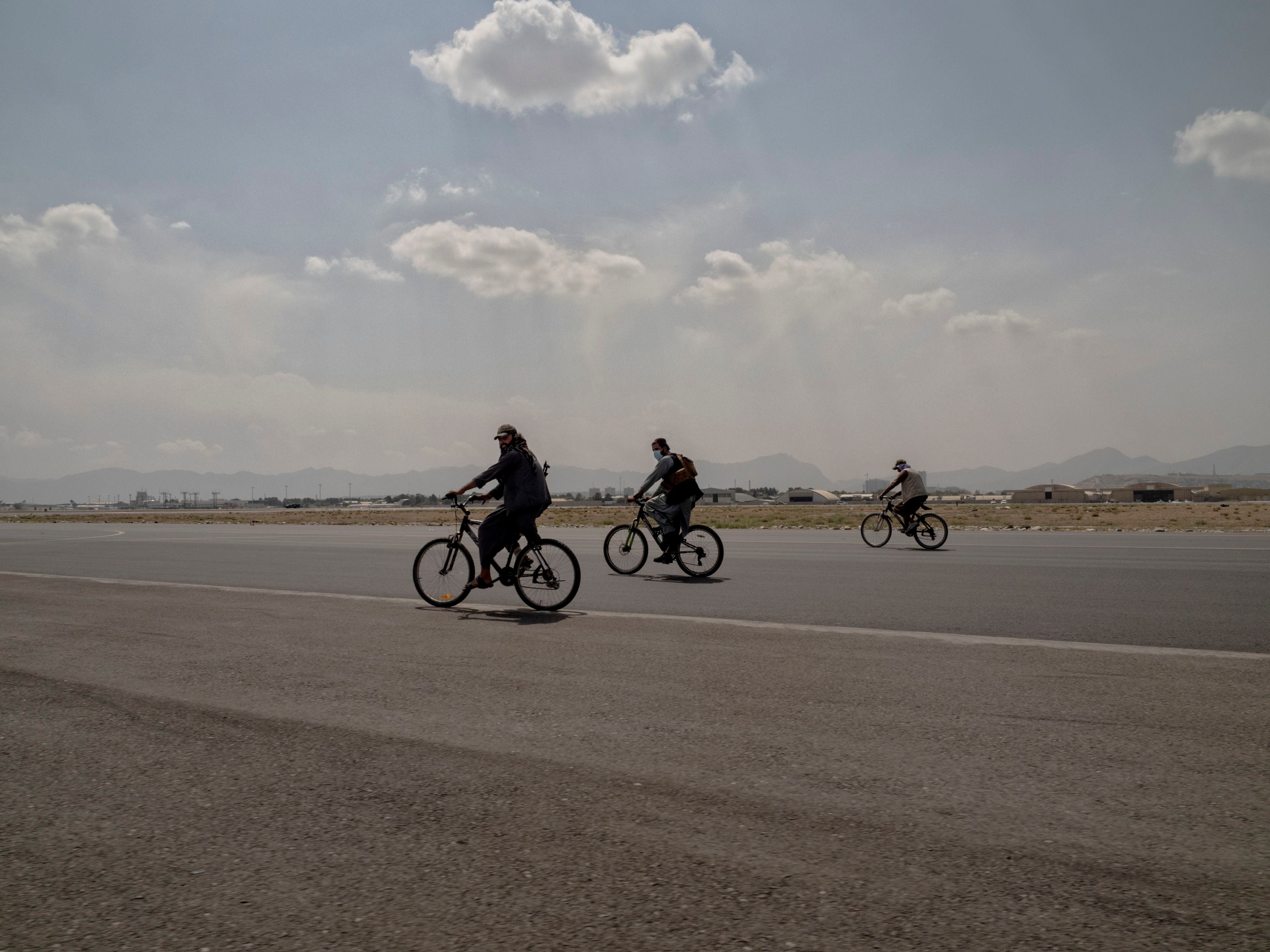 Vários talibãs pedalam na pista do Aeroporto Internacional Hamid Karzai na manhã seguinte à saída oficial dos Estados Unidos do país.