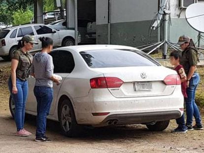 A mulher argentina sequestrada durante 32 anos (com blusão de cor cinza) entra em um carro de polícia com seu filho de 9 anos.