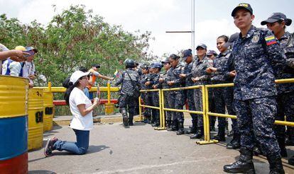Uma seguidora de Juan Guaidó se ajoelha diante de agentes da Guarda Nacional Bolivariana.