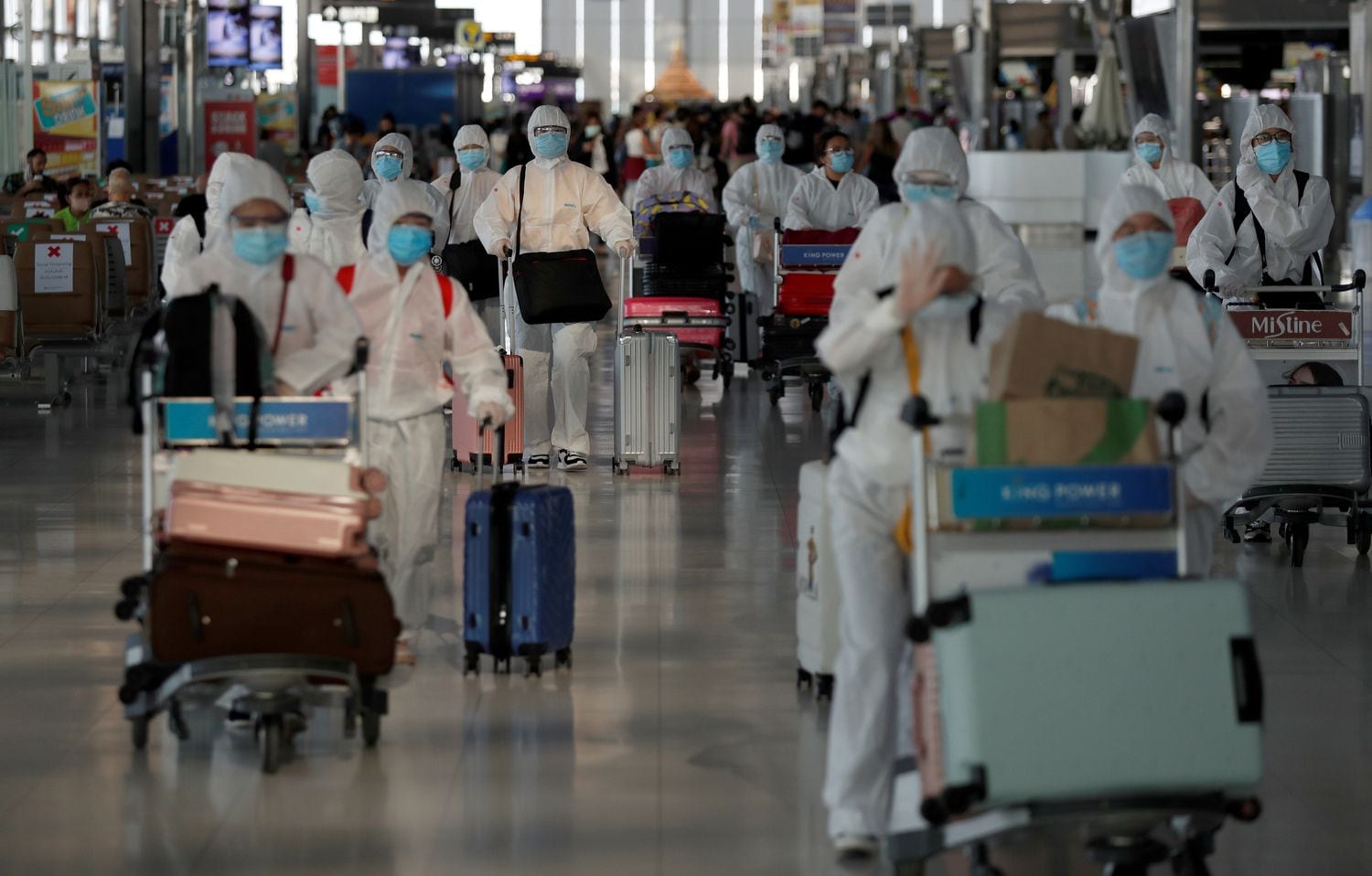 Estudantes chineses caminham pelo aeroporto de Suvarnabhumi, na Tailândia, com roupas de proteção após conseguirem a repatriação.