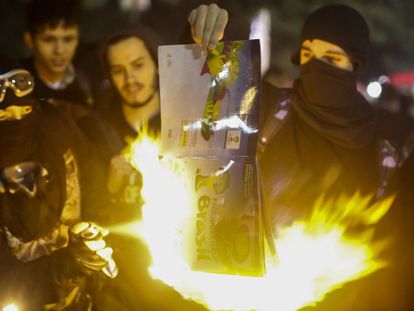 Manifestantes queimam um álbum de figurinhas da Copa.