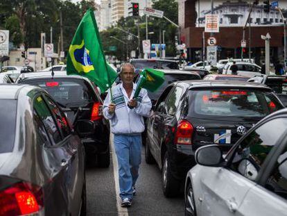 Um vendedor de bandeiras caminha entre os carros em São Paulo.