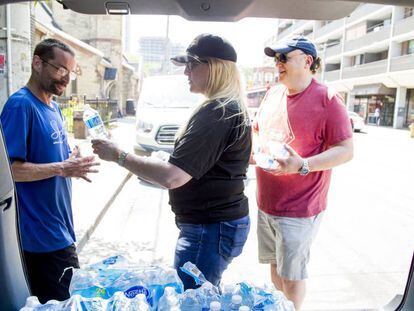 Uma mulher distribui garrafas de água em Toronto, no dia 30 de junho, durante a onda de calor no leste Canadá.