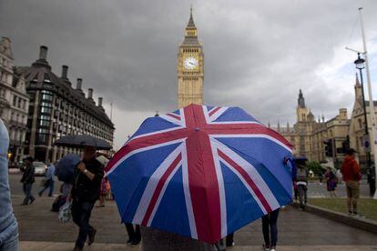 Uma pessoa passeia nas imediações do Parlamento Britânico com a bandeira do Reino Unido.