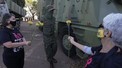Duas militantes que fizeram oposição à ditadura brasileira oferecem flores a militar, em Brasília.