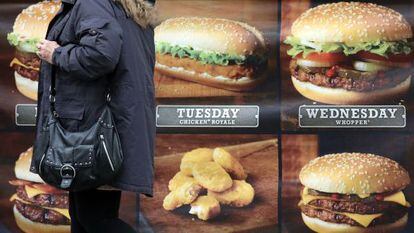 Uma mulher diante de um anúncio de fast food.