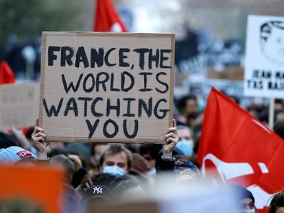 "França, o mundo está te observando", diz um cartaz na manifestação de sábado em Paris contra a lei de segurança, de Macron.