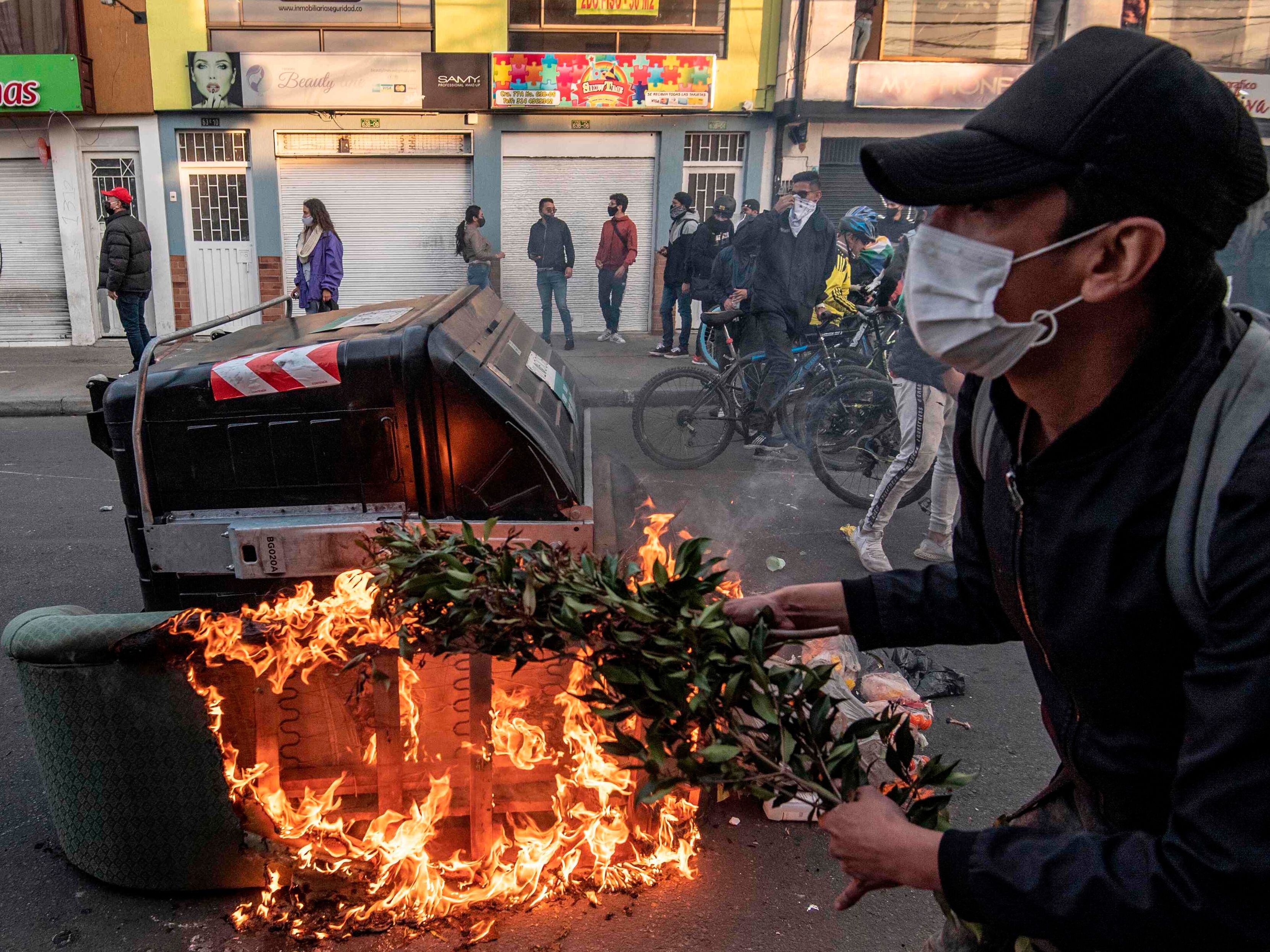Manifestante ateia fogo em barricadas durante os confrontos com a polícia em Bogotá, após a morte de advogado pelas forças de segurança.