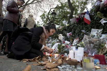 Uma mulher acende uma vela em frente ao Bataclan em Paris.