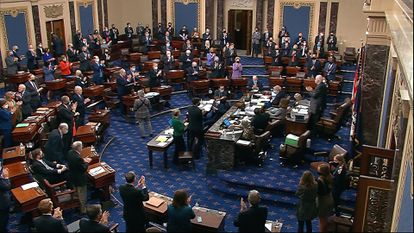 Senadores aplaudem o resultado da votação do plano de resgate, neste sábado, em Washington.