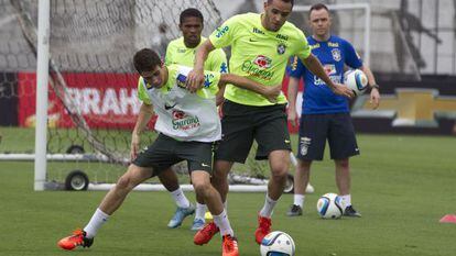 Oscar e Renato Augusto disputam a bola durante treino.
