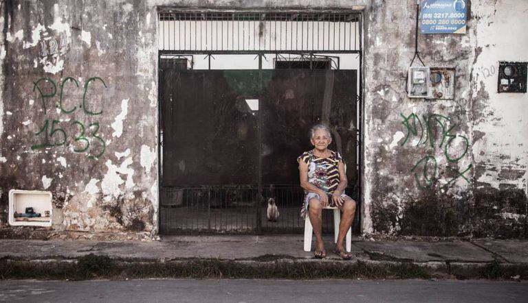 Moradora do bairro do Pirambu, em Fortaleza, ao lado de pichação do PCC.