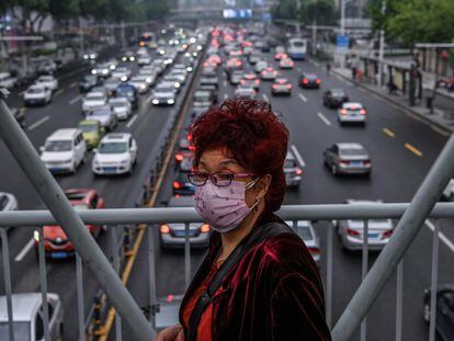 Mulher protegida por máscara cruza por uma passarela em Wuhan, em 14 de maio.
