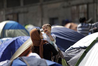 Uma imigrante segurando um bebê na quarta, no porto de Pireu.