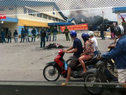 Motociclistas passam por policiais que vigiam a área onde se encontra uma fábrica incendiada na província vietnamita de Binh Duong.