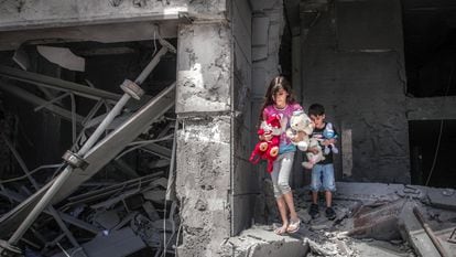 Crianças palestinas resgatam brinquedos na casa onde viviam, que ficou gravemente destruída pelos ataques aéreos israelenses em Gaza no dia 17 de maio de 2021.