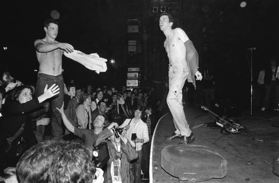 Joe Strummer trocando a camiseta com alguém do público em um show do The Clash em 1977.