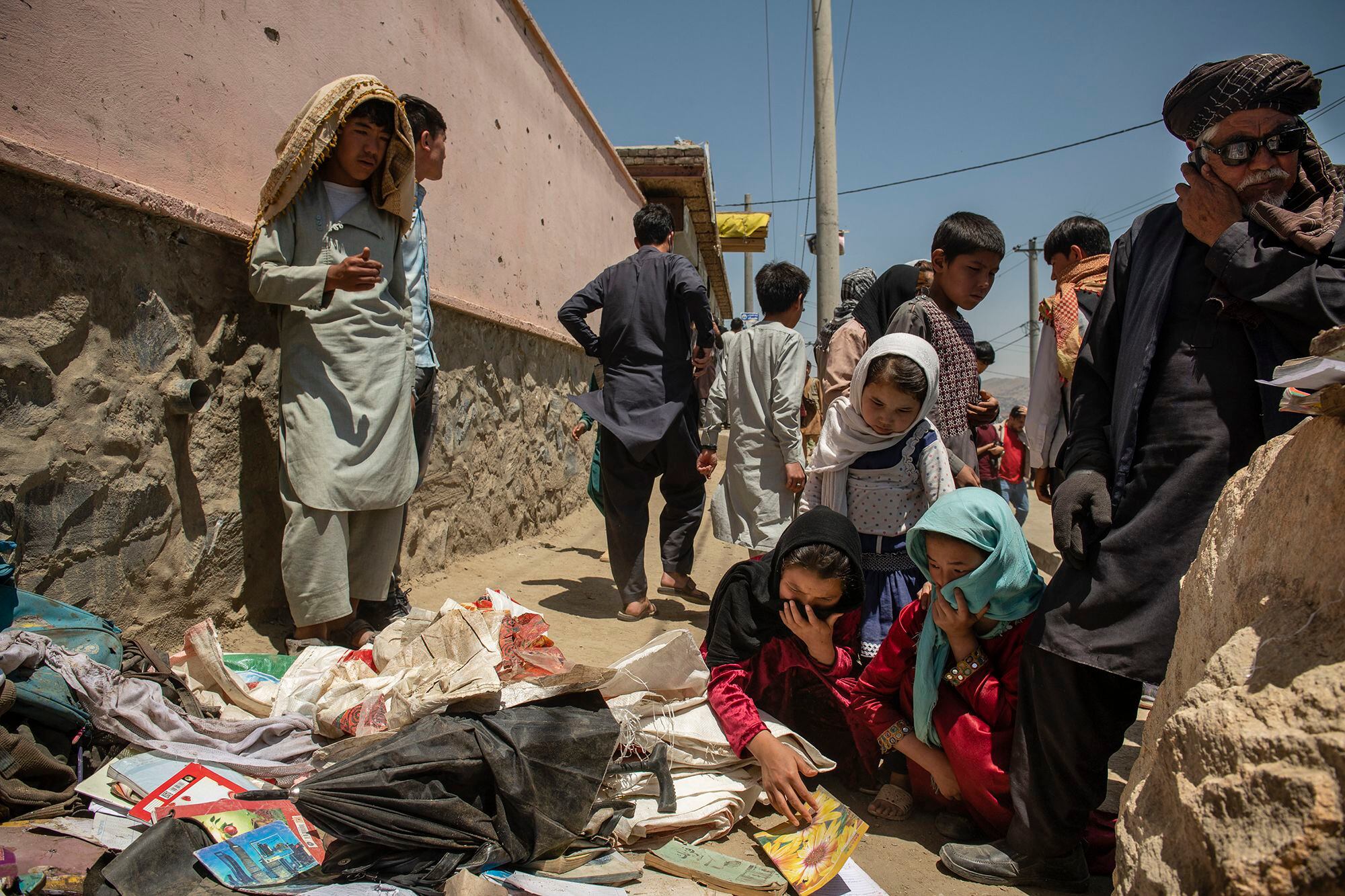 Afegãos desolados após um atentado da insurgência contra uma escola em Cabul em maio.
