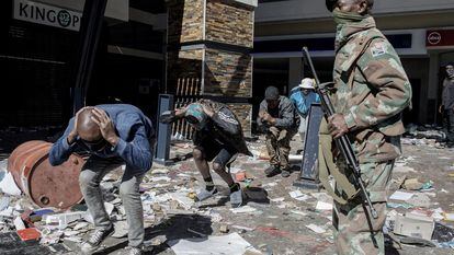 Militar vigia homens detidos por saque em um centro comercial de Soweto no dia 13.