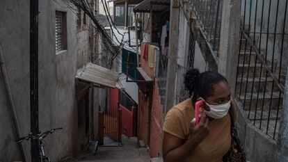 Uma mulher com uma máscara fala ao telefone em Paraisópolis, em São Paulo, no último 6 de maio.
