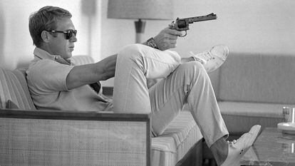 Steve McQueen, sentado no sofá de sua casa em Palm Springs (Califórnia) com uma pistola na mão, em maio de 1963.