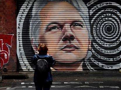 Mulher fotografa muro com imagem de Julian Assange em Melbourne, na Austrália, nesta terça.
