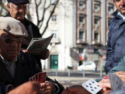Aposentados portugueses jogam cartas em um parque de Lisboa.