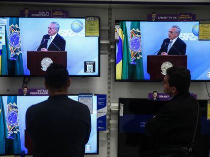 Dois homens assistem ao discurso de Temer, nesta quinta.