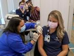 Certified Nurse Assistant Kisa Kniola, left, gives a COVID-19 vaccination to Registered Nurse Lindsay Kreighbaum at Franciscan Health, Friday, Dec. 18, 2020, in Michigan City, Ind. (John Luke/The Times via AP)