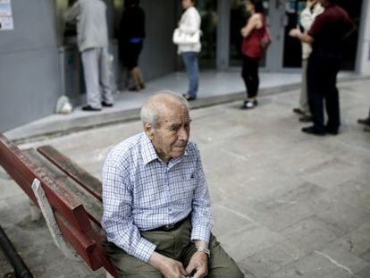 Um pensionista, sentado na fila de um caixa na Grécia.