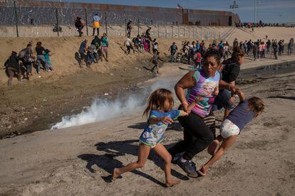 Maria Meza, uma hondurenha de 40 anos, tenta evitar junto aos filhos o gás lacrimogêneo lançado contra uma caravana de imigrantes em Tijuana, na fronteira com os EUA, em dezembro de 2018.