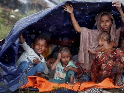 Refugiados da etnia rohingya se protegem da chuva com um plástico no campo de Cox’s Bazar, em Bangladesh
